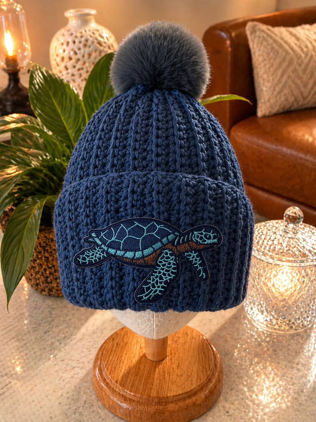 Navy blue crocheted beanie with pom pom pom pom displaying an embroidered sea turtle&nbsp;