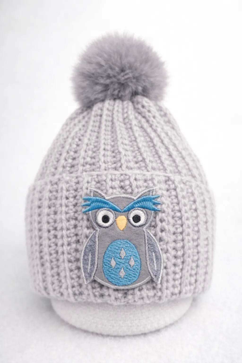 Grey ribbed baby beanie with an owl patch.
