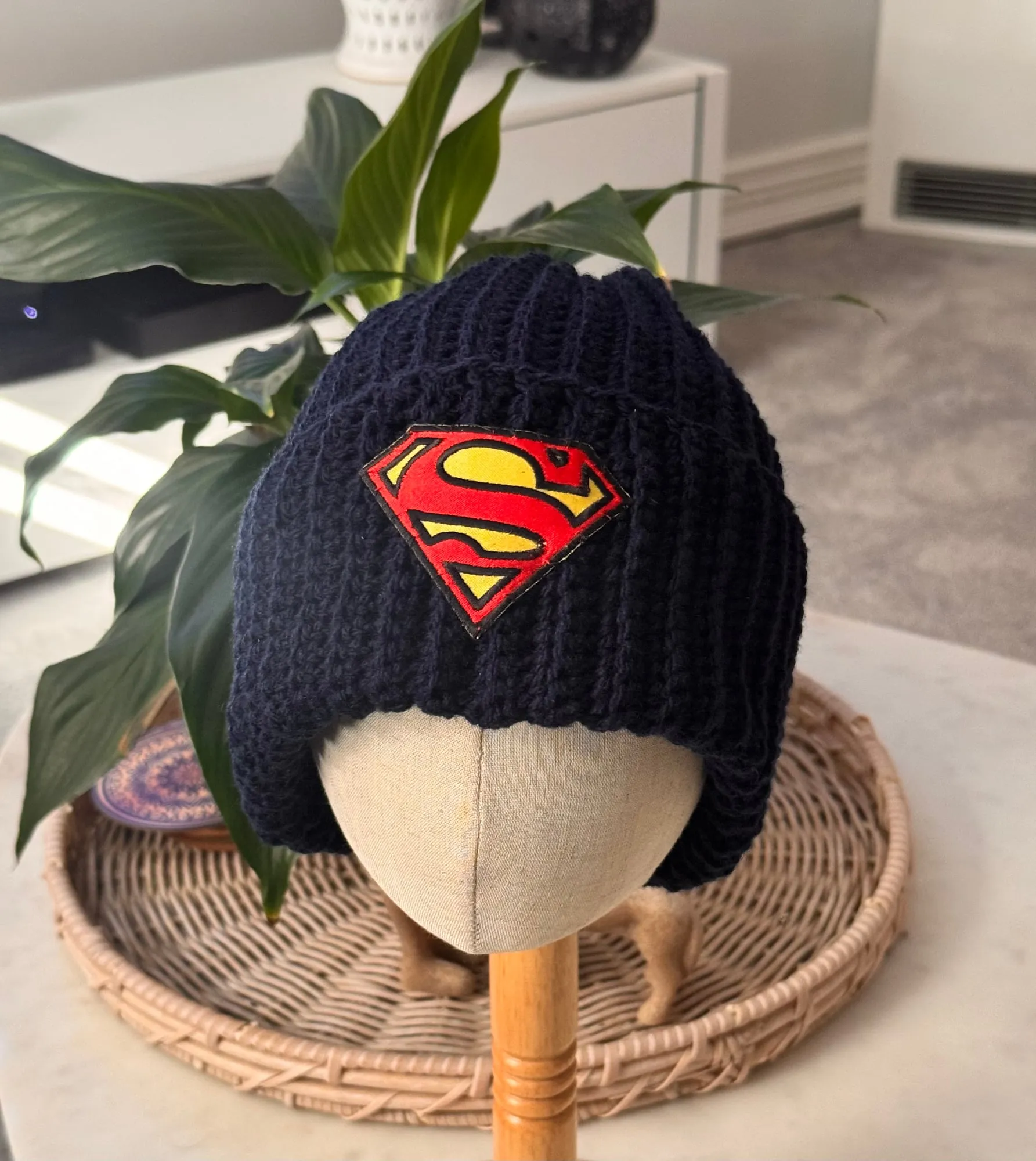 Navy blue crocheted beanie with ribbed texture and a red and yellow Superman logo patch on the front