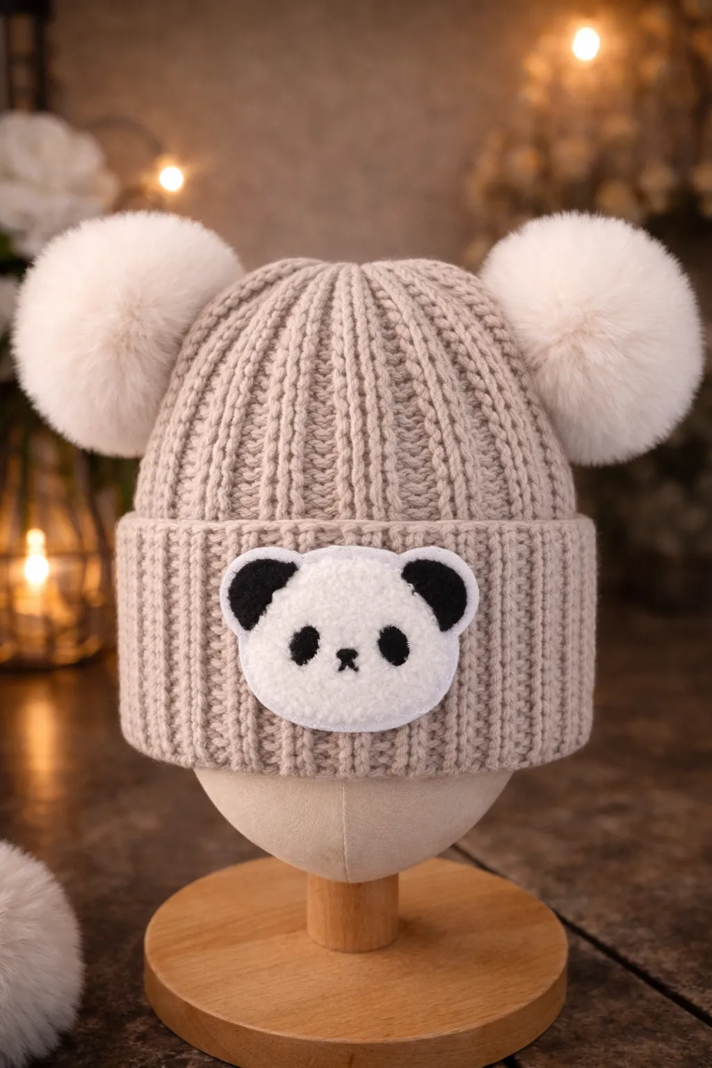 An oatmeal-coloured kids beanie with panda-ear crochet details and a matching pom pom.